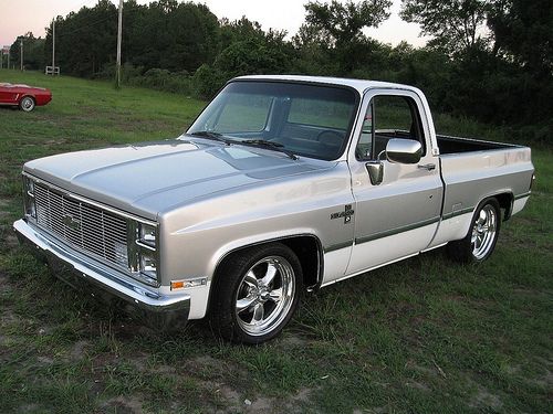 a silver pickup truck parked on top of a grass covered field