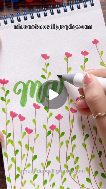 someone is drawing flowers on paper with marker and pen while they are doing something in front of them