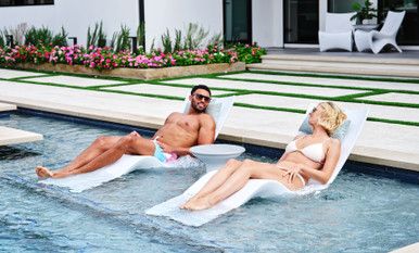 two people lounging on lounge chairs next to a pool