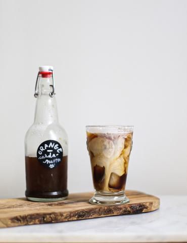 there is a bottle and a glass on the table next to each other, with ice in it