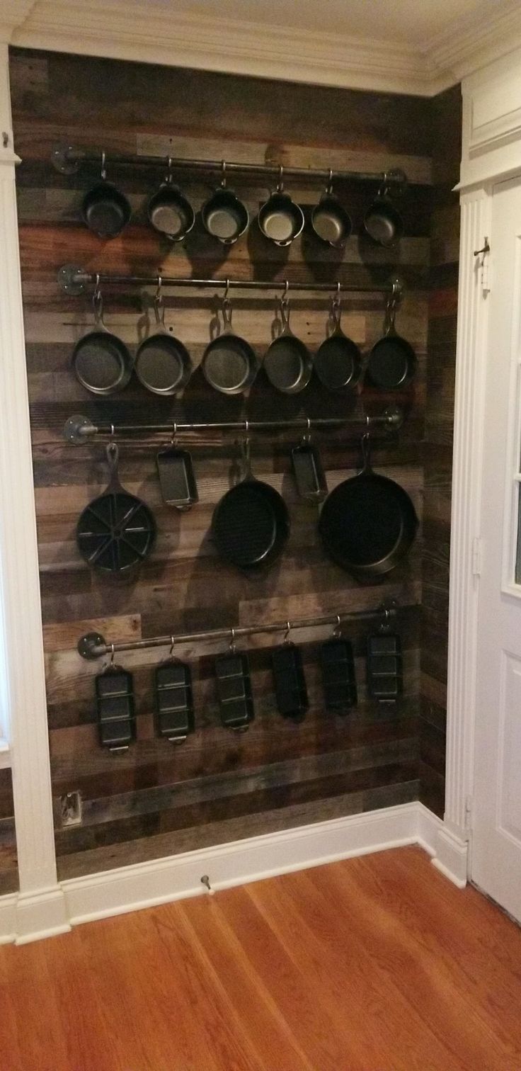 pots and pans are hanging on the wall in this kitchen with wood flooring