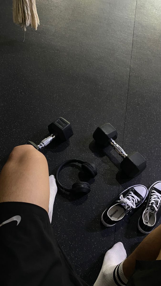 someone is sitting on the floor with their feet up and some dumbbells in front of them