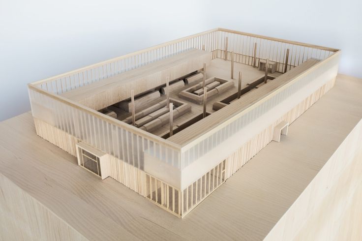 an architectural model of a building on top of a wooden table in front of a white wall