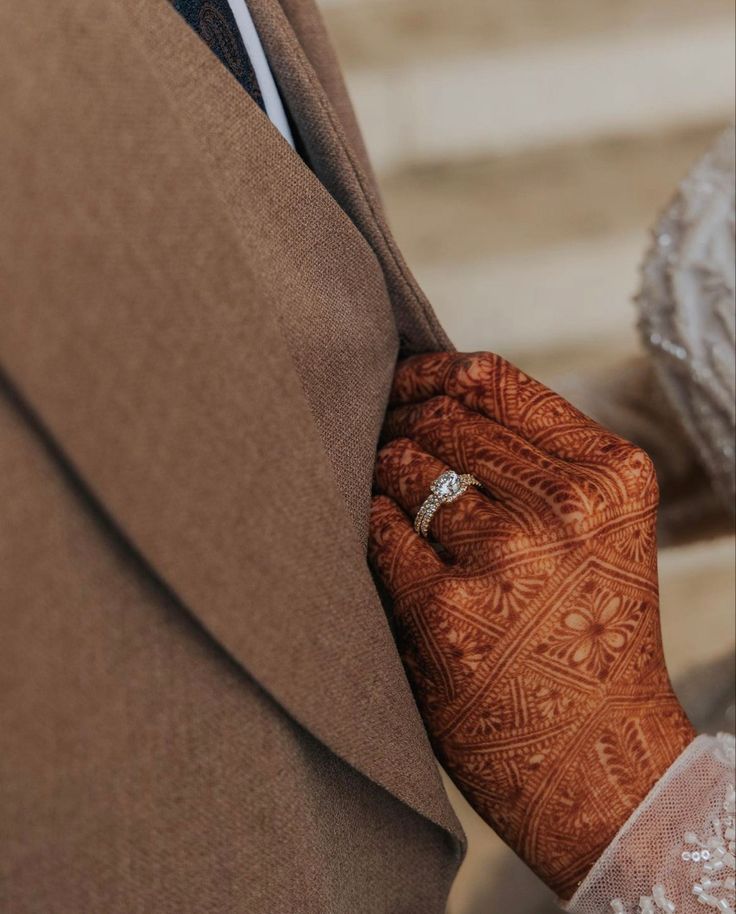 a close up of a person wearing a suit and tie with a ring on their finger