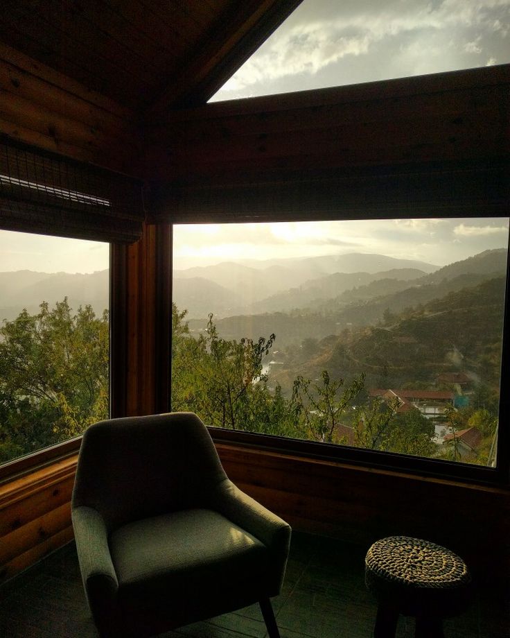 a chair sitting in front of a large window overlooking the mountains and valleys below it