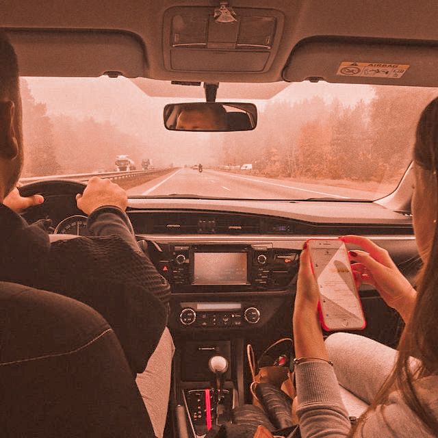 two people driving in the back seat of a car