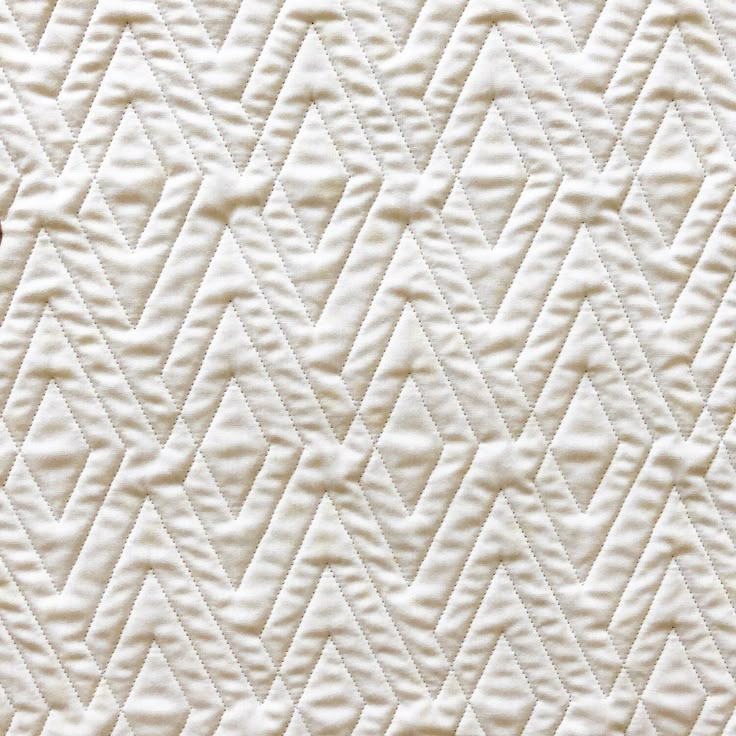 an up close view of a quilted material with white stitching on the edges