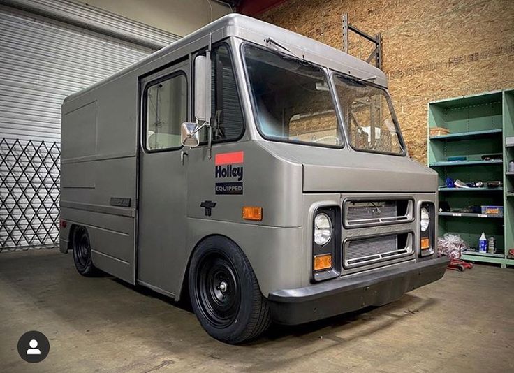 a grey truck parked in a garage next to some shelves and shelving unit doors