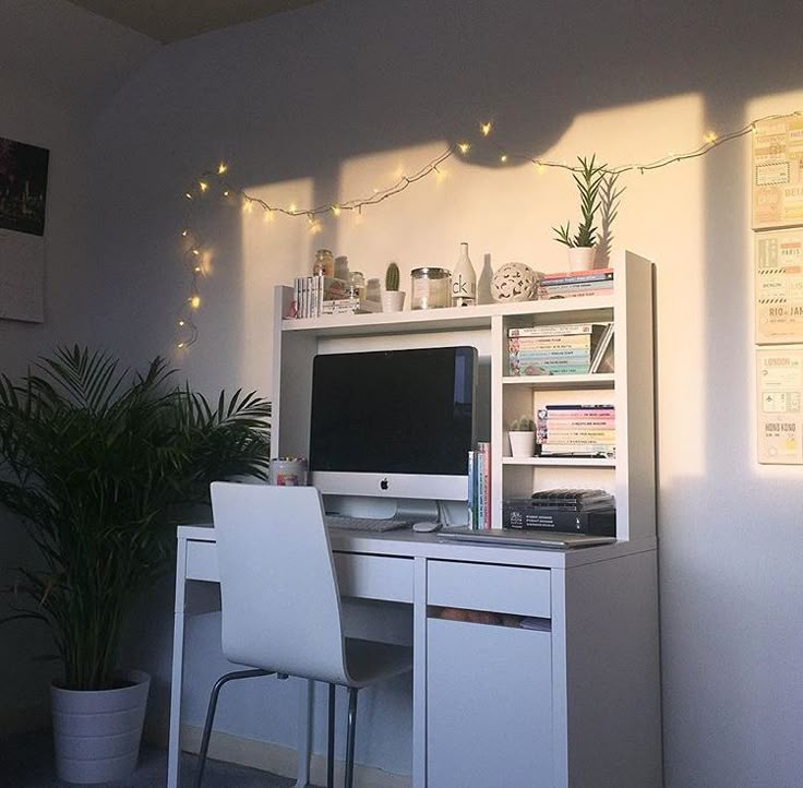 a white desk with a computer on top of it next to a potted plant