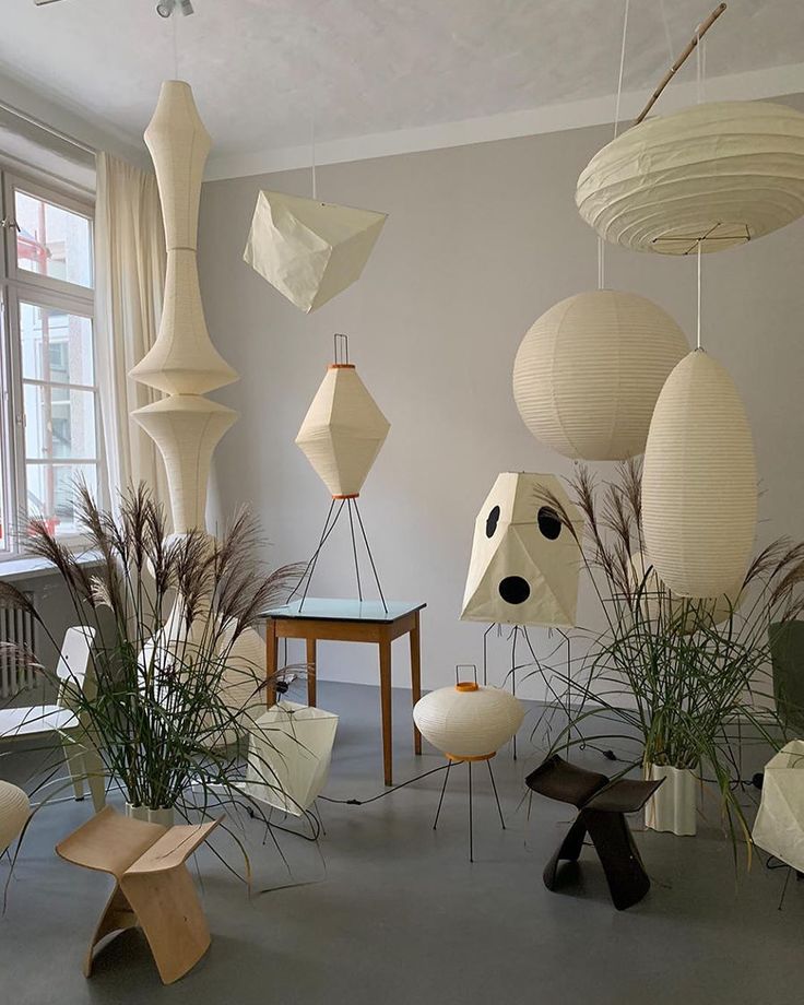 a room filled with lots of different types of paper lanterns hanging from the ceiling and plants