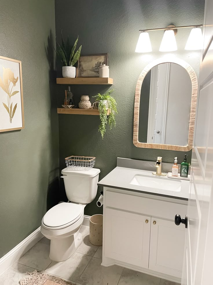 a white toilet sitting next to a sink in a bathroom under a mirror and lights