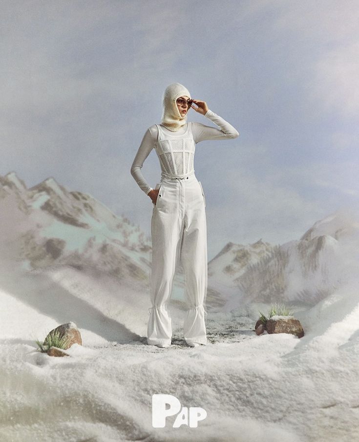 a woman in white standing on top of snow covered ground