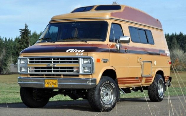 an orange and brown truck parked on the side of a road in front of trees