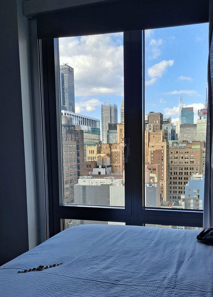 a bedroom with a view of the city from it's window sill and bed