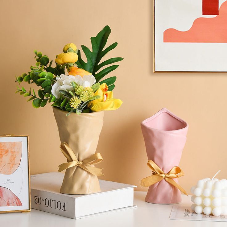 a bouquet of flowers in a vase sitting on a table next to a box with candles