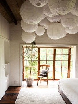 a bedroom with white paper lanterns hanging from the ceiling and a chair in the corner