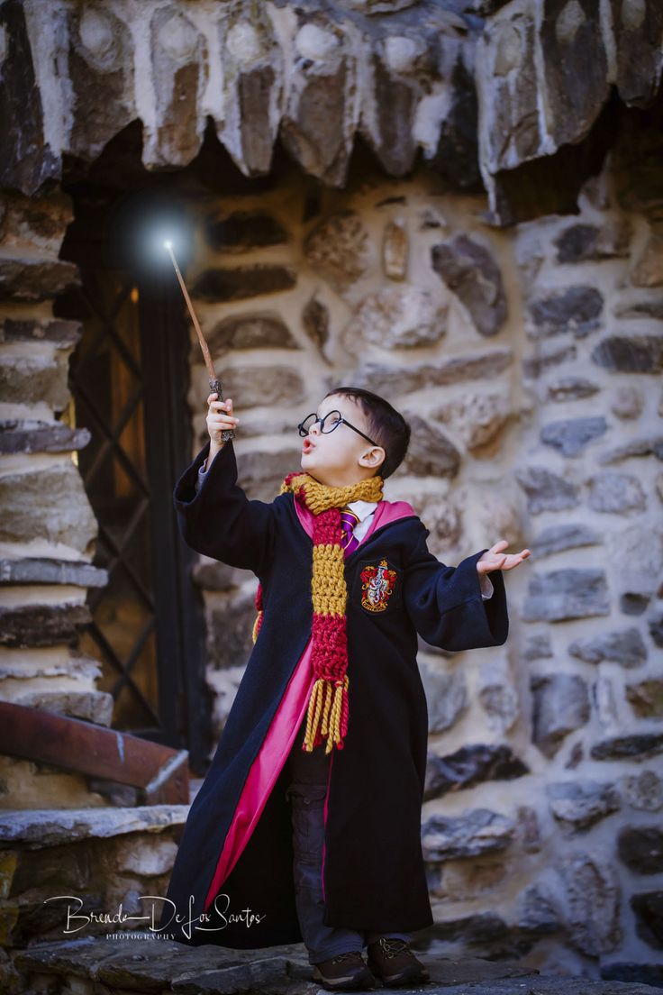 a young boy dressed in harry potter costume holding a wand and looking up at the sky