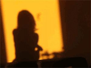 the shadow of a woman's head on a wall next to a vase with flowers