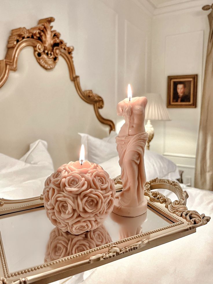 a candle that is sitting on top of a table in front of a mirror with an angel figurine