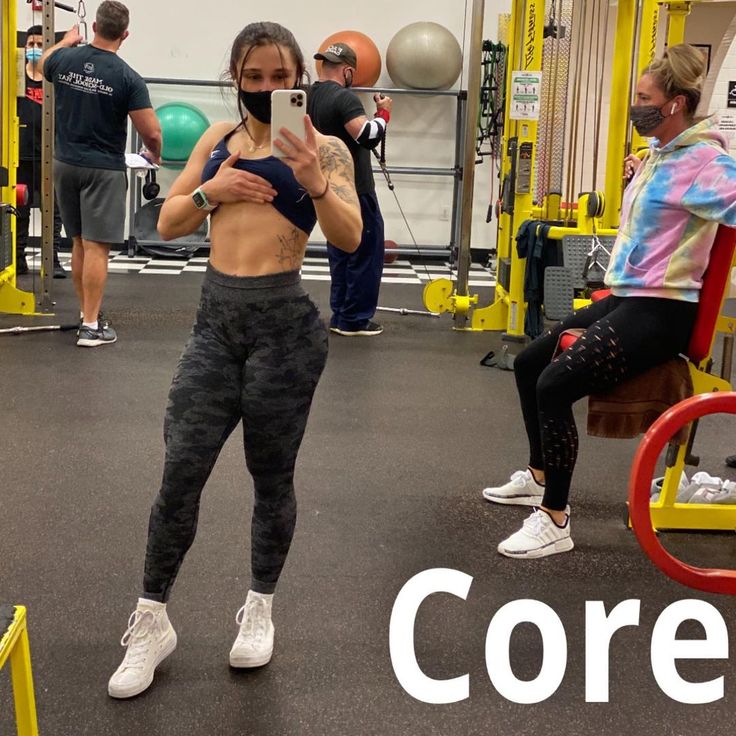 a woman taking a selfie in the gym with her cell phone and other people