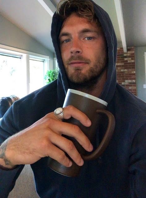 a man in a hoodie holding a coffee cup