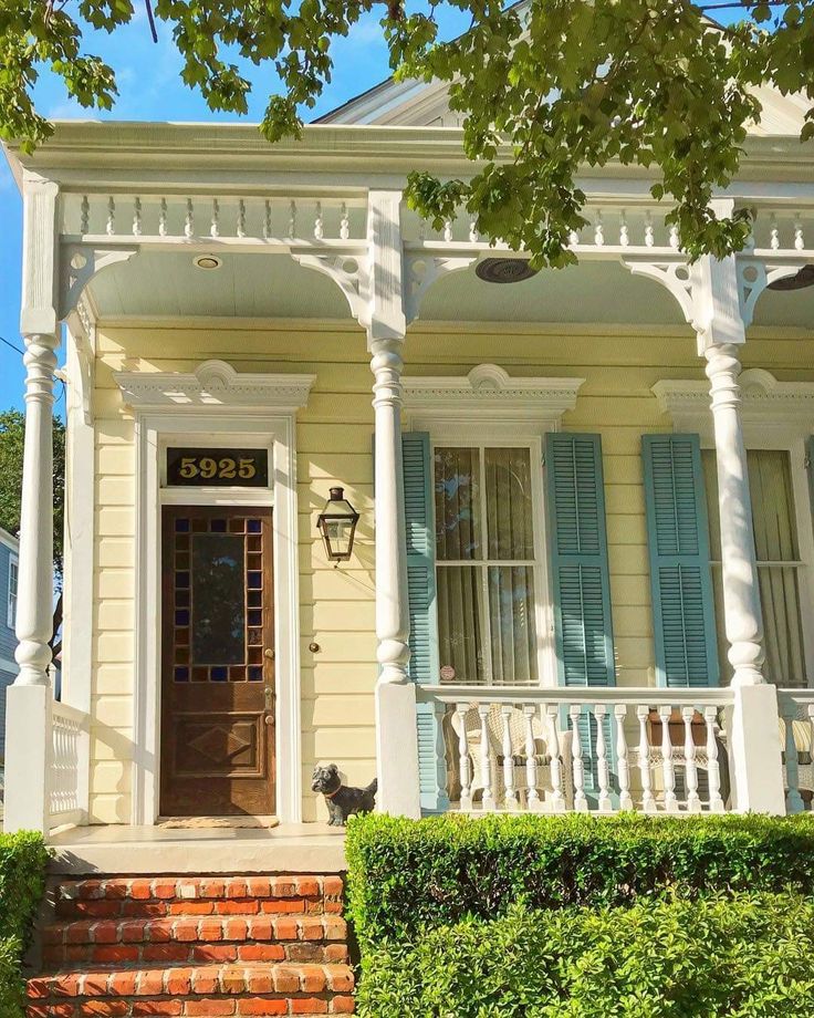 a yellow house with blue shutters on the front door and steps leading up to it