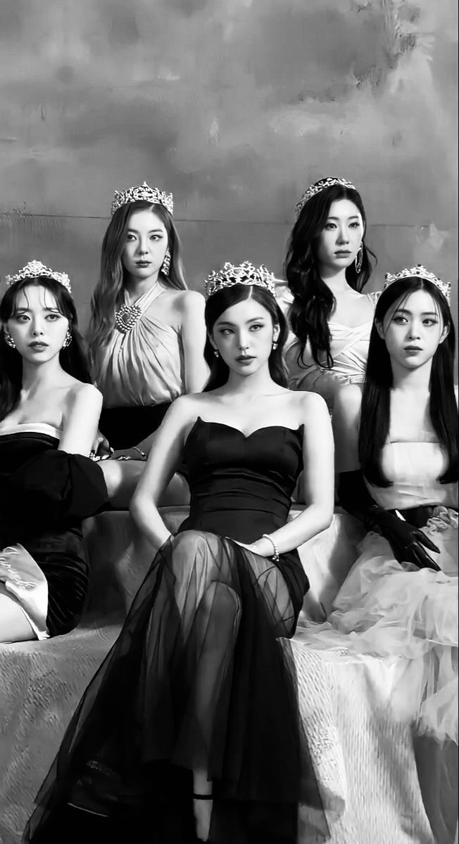 black and white photograph of four women in evening dresses sitting on a bed with their arms around each other