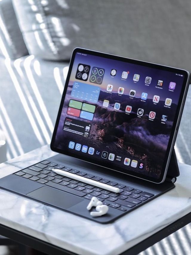 an open laptop computer sitting on top of a white marble table next to a keyboard