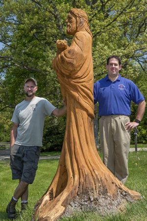 two men standing next to a wooden statue