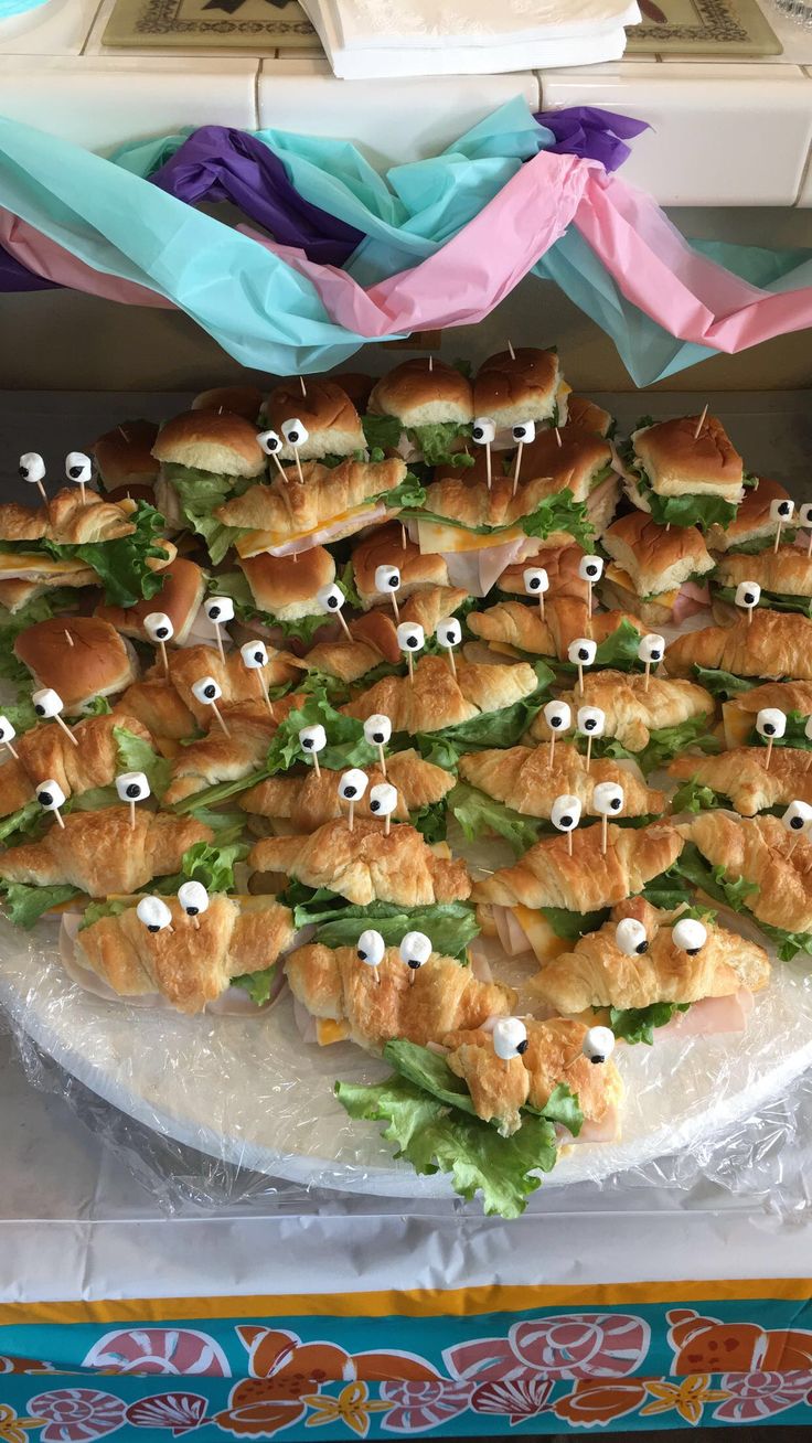 sandwiches with googly eyes are arranged on a platter at a party or event