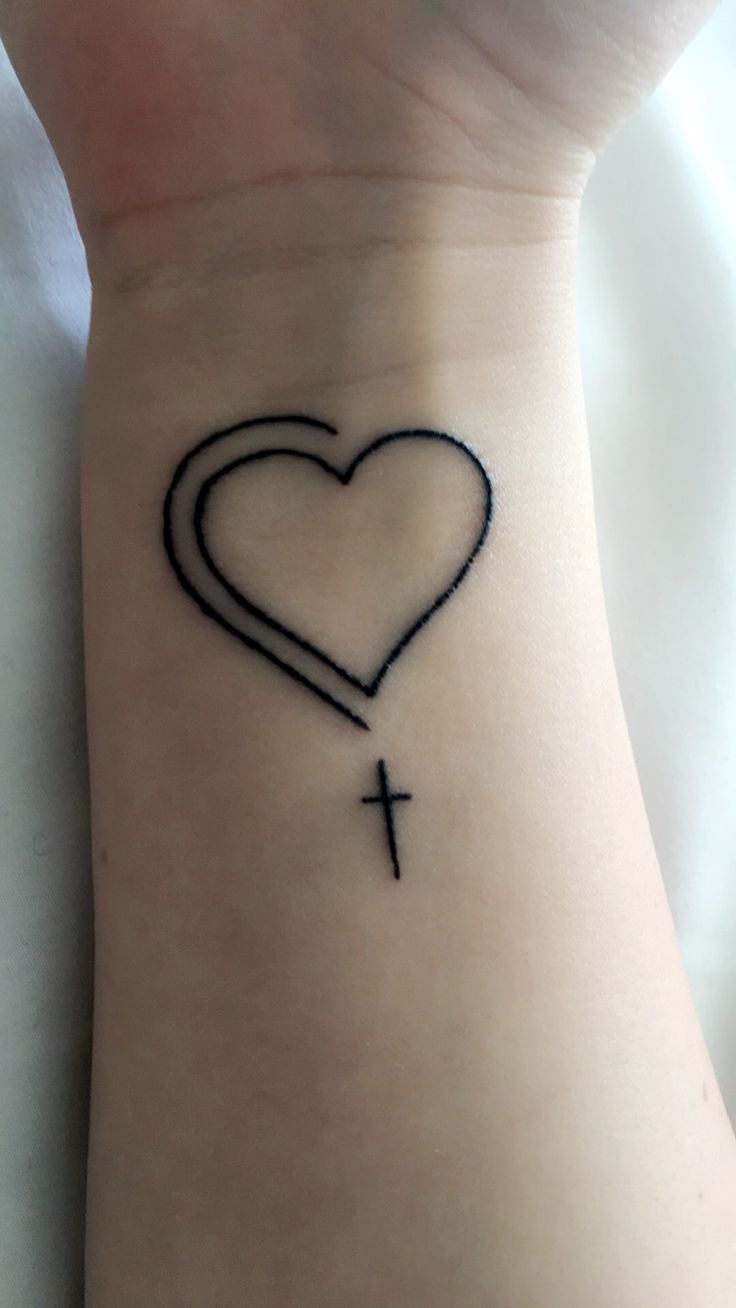 a heart with a cross tattoo on the wrist