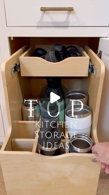 a person is opening the bottom drawer of a kitchen cabinet with lots of items in it