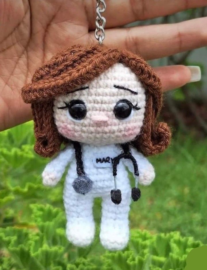 a crocheted doll is being held in the air by someone's hand