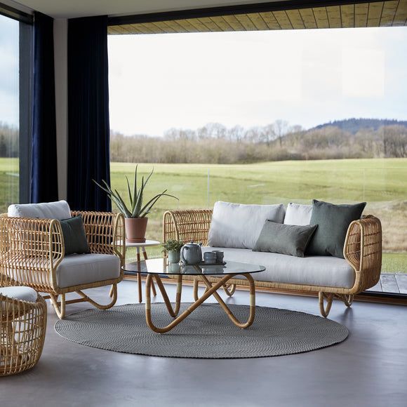 a living room with wicker furniture and large windows