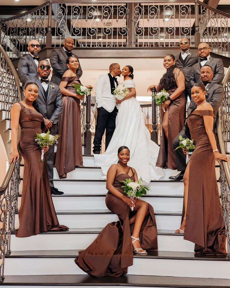 the bride and groom are posing on the stairs with their bridal party in brown dresses