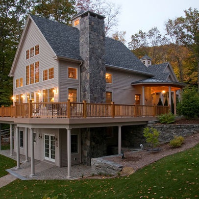 a large house with a deck and lights on it's windows is lit up in the evening