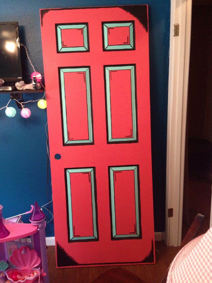 a red door in the corner of a room with blue walls and toys on the floor