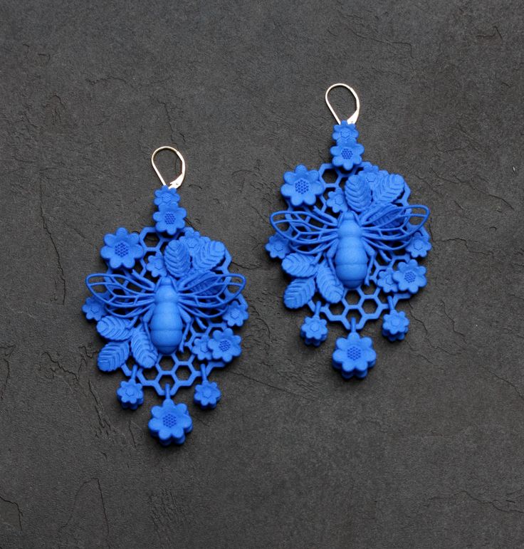 two pairs of blue earrings sitting on top of a black surface