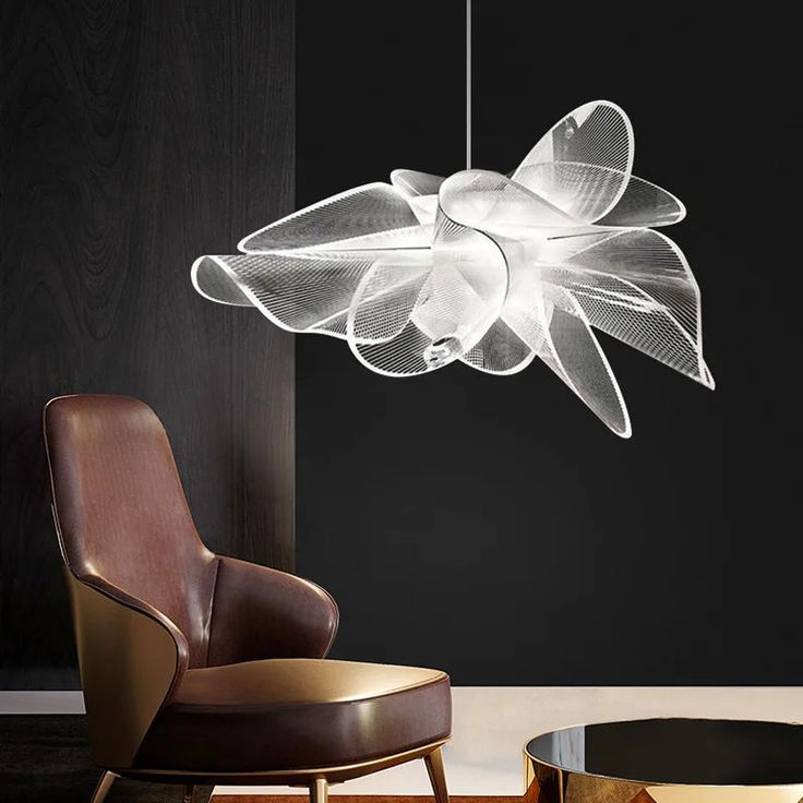 a modern chandelier hanging from the ceiling in a room with black walls and leather chairs