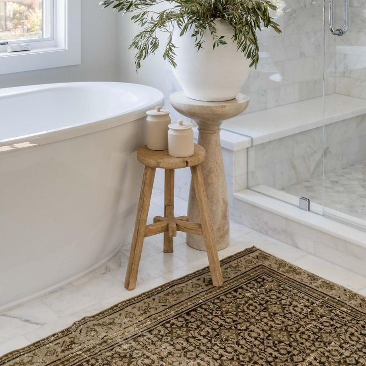 a white bath tub sitting next to a wooden stool