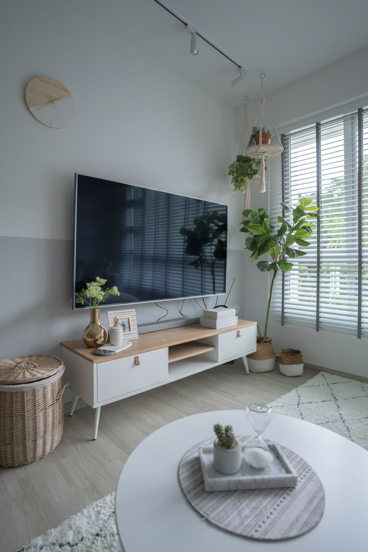 a flat screen tv sitting on top of a white entertainment center next to a window