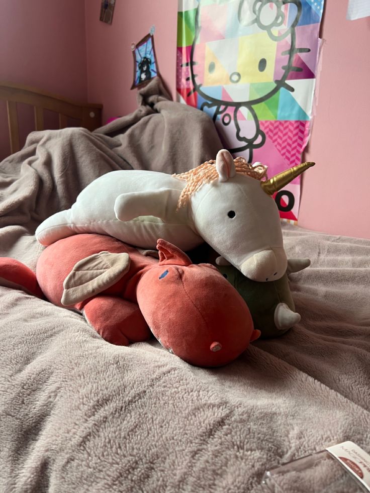 a stuffed unicorn laying on top of an orange and pink pillow in a child's bedroom