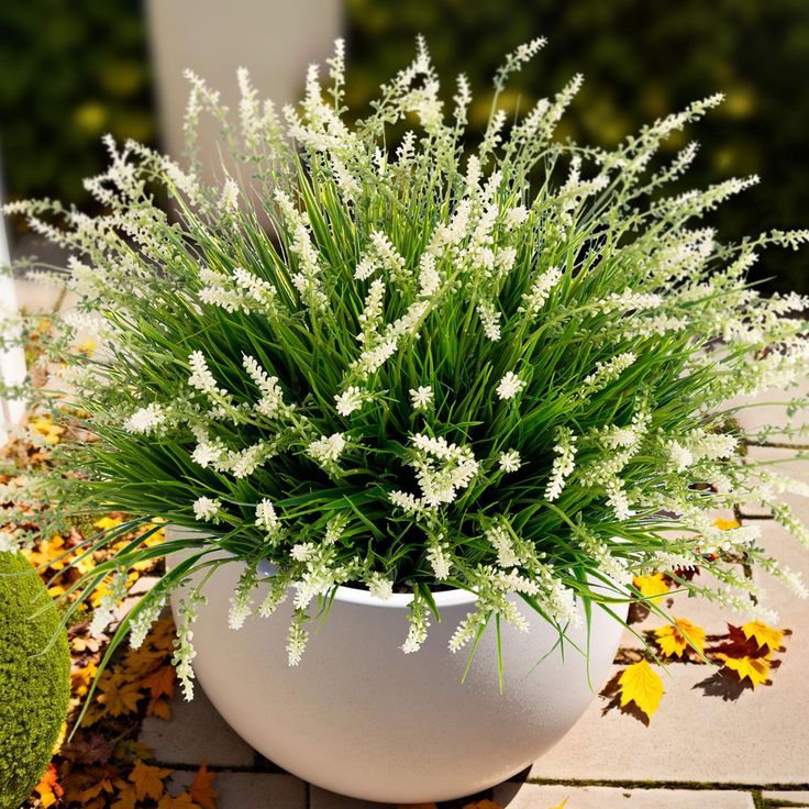 a white planter filled with lots of flowers sitting on top of a brick floor