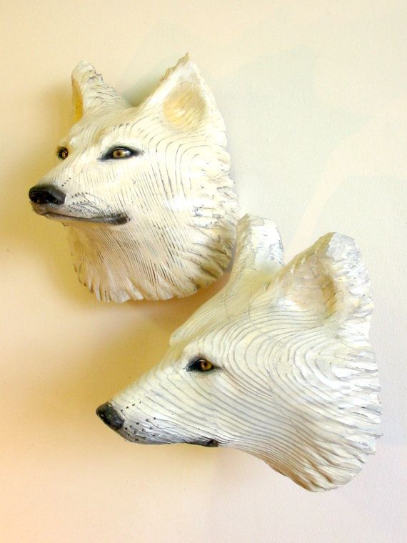 two white ceramic wolf heads mounted on a wall