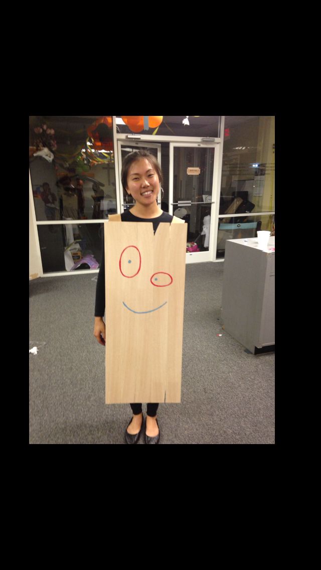 a woman holding a cardboard bag with a smiley face drawn on it and standing in an office