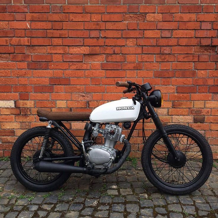 a white and black motorcycle parked next to a brick wall