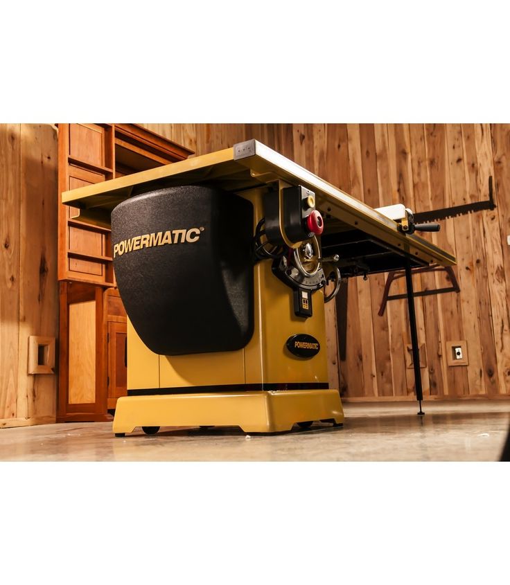 a table sawing machine sitting on top of a hard wood floor next to a wooden wall