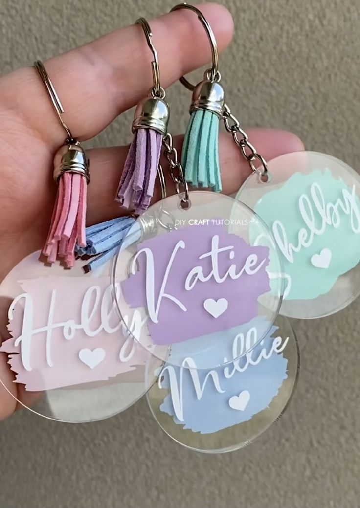 three keychains with tassels on them in the shape of hearts and words