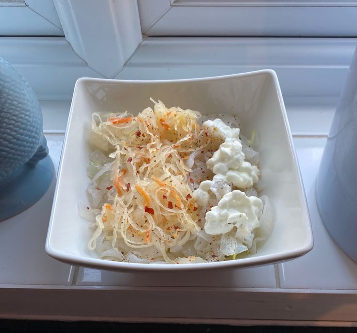 a white bowl filled with food sitting on top of a counter next to a window