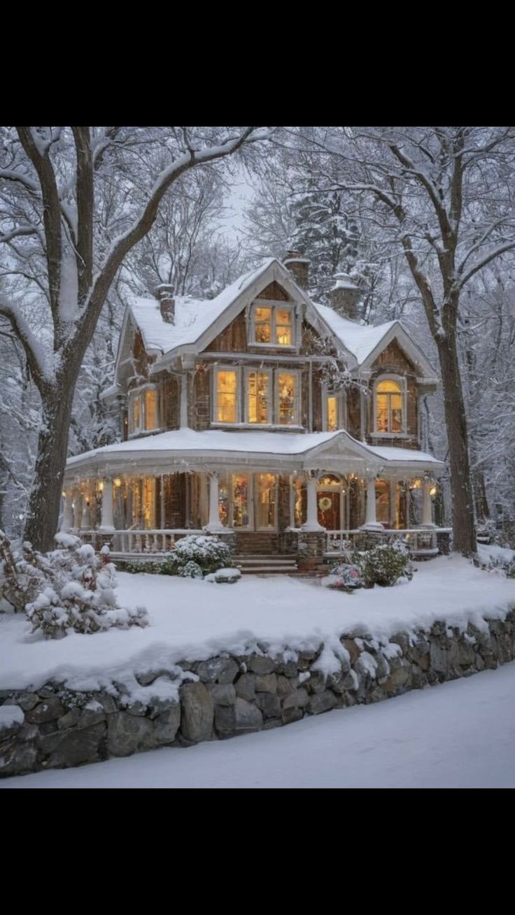 a large house with lots of windows and lights on it's front porch in the snow